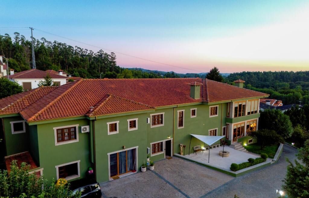 A two-story building with a red-tiled roof, a covered patio area, and a view of the surrounding landscape.