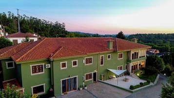 A two-story building with a red-tiled roof, a covered patio area, and a view of the surrounding landscape.