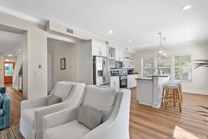A modern kitchen with white cabinetry, stainless steel appliances, and a bar area with stools. - Adorable Old Seagrove Beach Cottage Bordering Seaside Near Beach Access (Santa Rosa Beach)