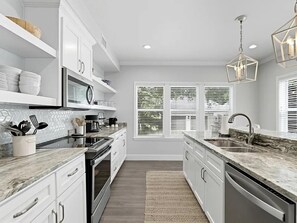 A modern kitchen with white cabinetry, a granite countertop, a built-in oven, and a dishwasher. - Adorable Old Seagrove Beach Cottage Bordering Seaside Near Beach Access (Santa Rosa Beach)