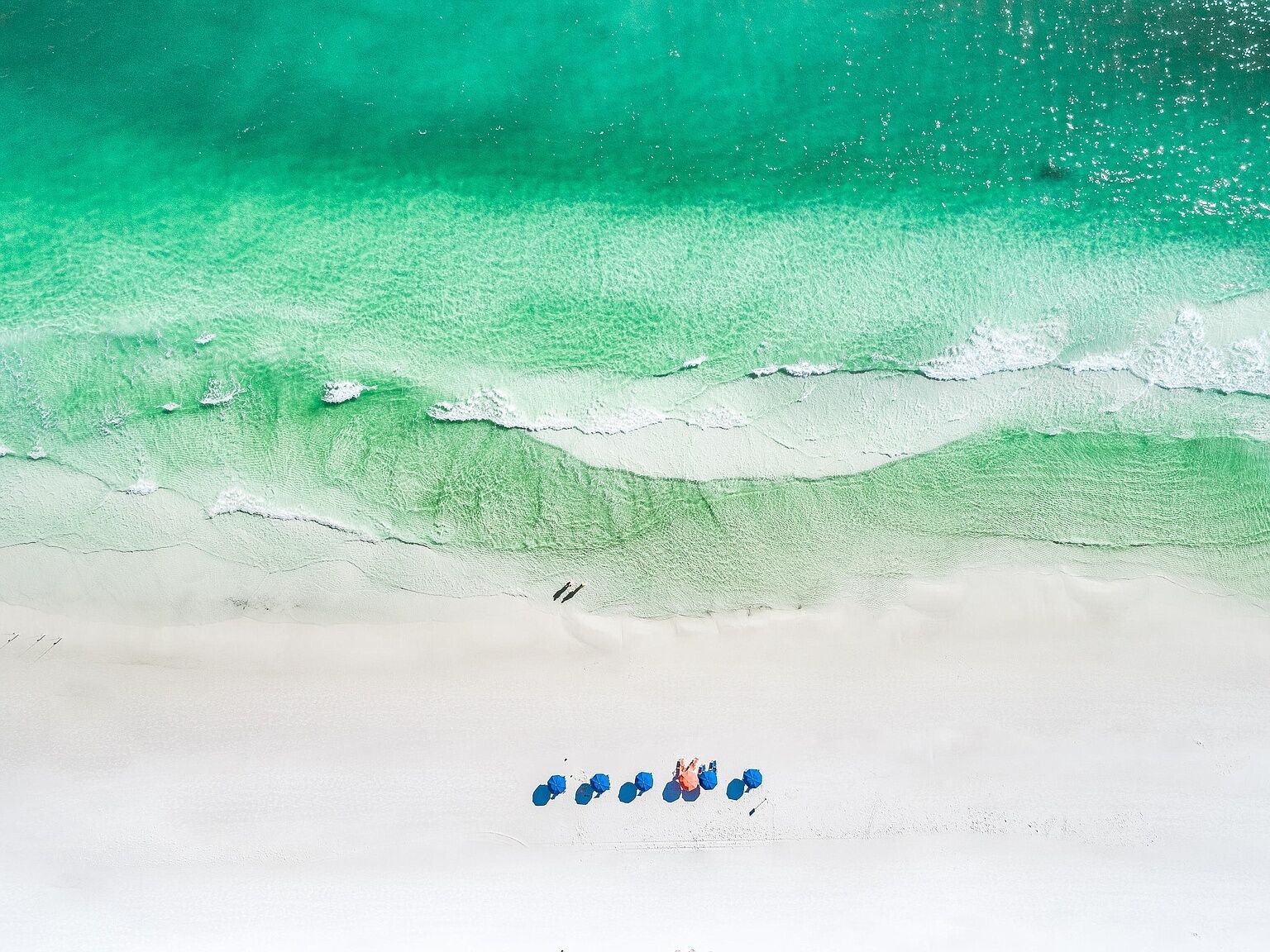 A beach with clear turquoise water and white sand.