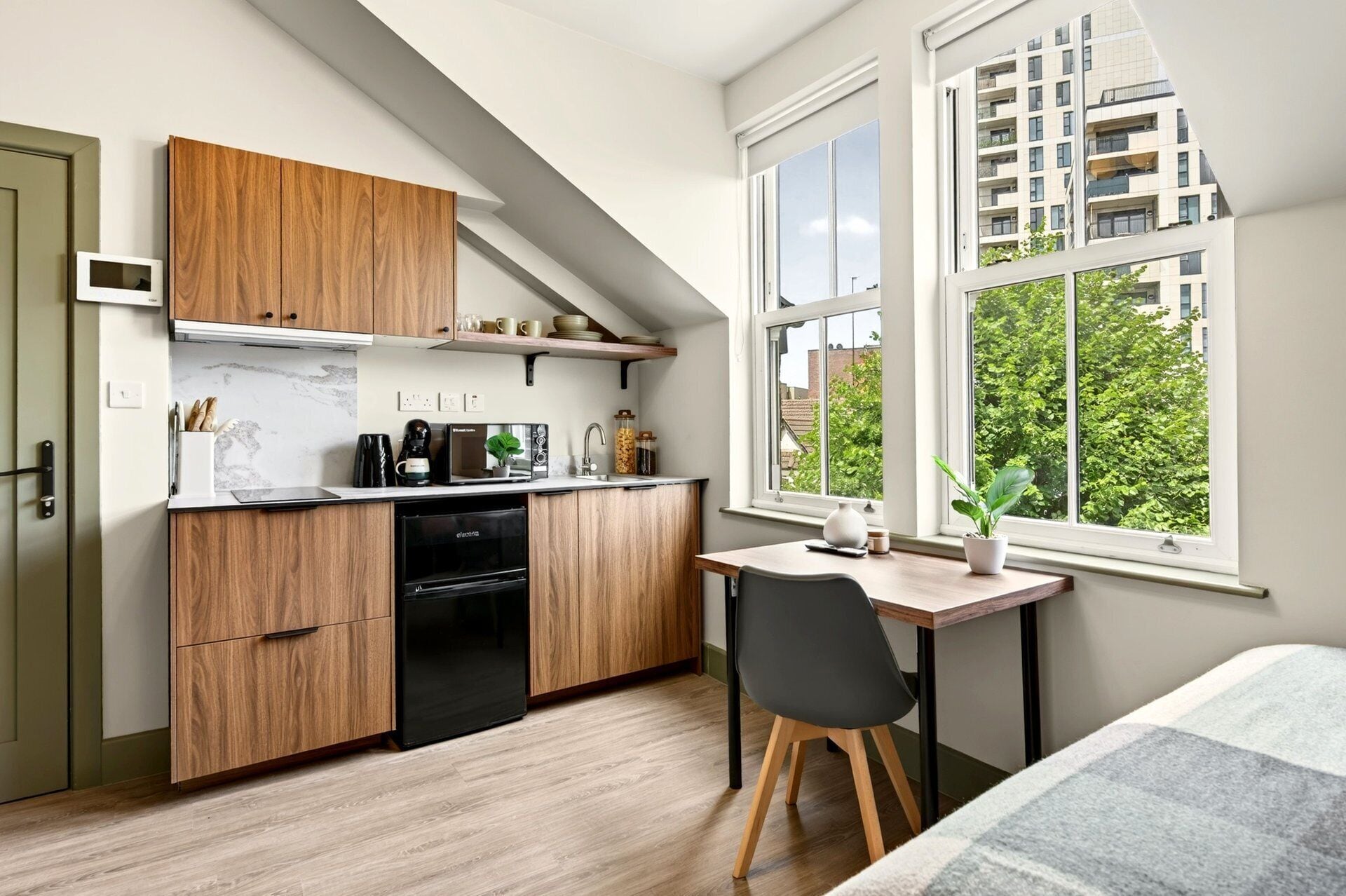 A compact kitchen with wooden cabinets, a built-in oven, and a dining area with a table and chair.