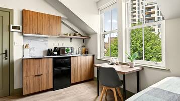 A compact kitchen with wooden cabinets, a built-in oven, and a dining area with a table and chair.
