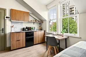 A compact kitchen with wooden cabinets, a built-in oven, and a dining area with a table and chair.