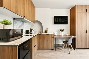 Cocina moderna con armarios de madera, microondas integrado, cafetera y un letrero que dice 'GUEST READY'.