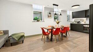 Eine moderne Küche mit schwarzen Schränken, einem eingebauten Backofen und einem Essbereich mit einem Holztisch und roten Stühlen.