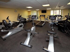 A gym with multiple cardio machines including treadmills and ellipticals, carpeted flooring, and a clock on the wall. - Azure #208 | Near Beach, Beautiful Views + Amenities (Fort Walton Beach)