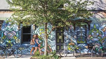 A street scene with a building featuring colorful graffiti art, a tree, and bicycles parked in front.