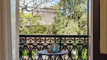 A wooden deck with a metal railing, a small round table, and two chairs.