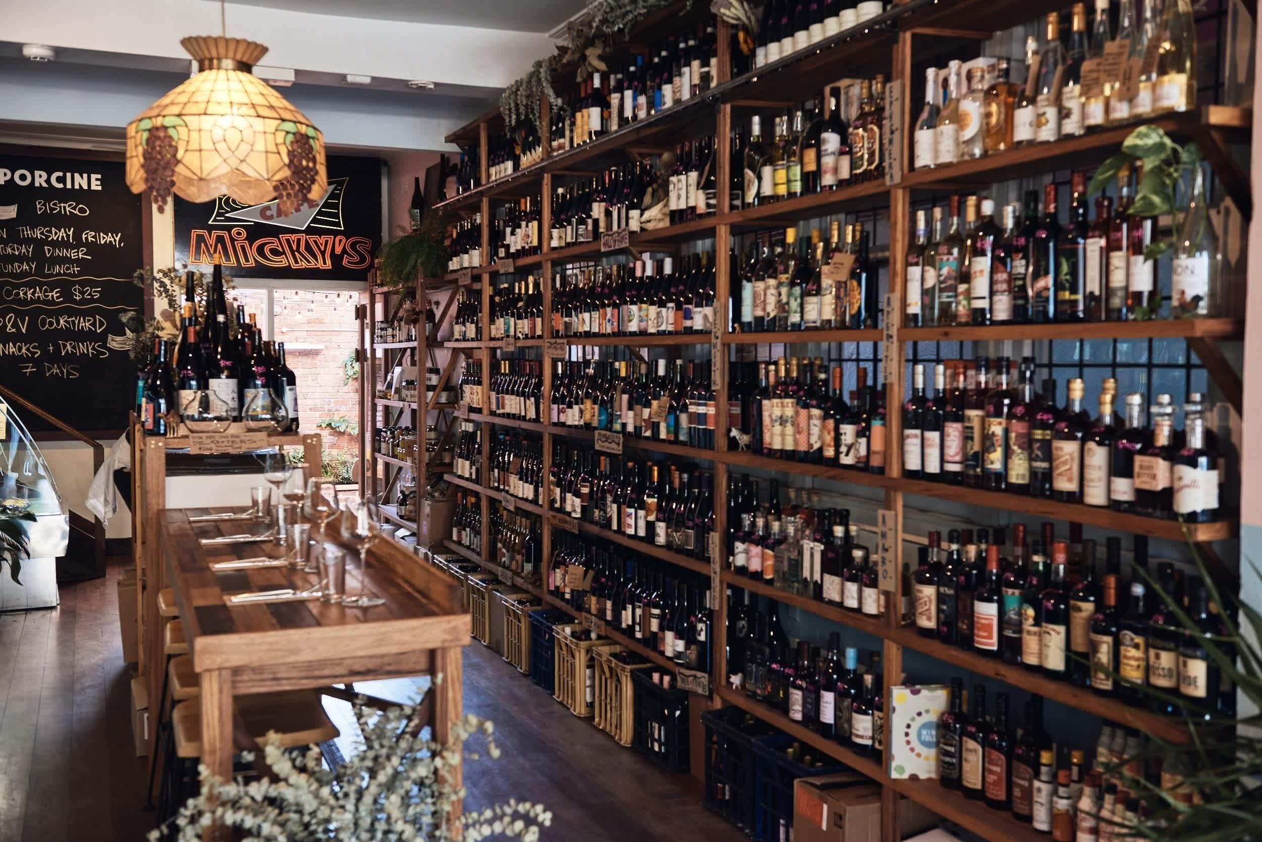 A bar with wooden shelves stocked with various bottles, a chalkboard menu, and a hanging light fixture.