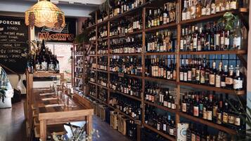 A bar with wooden shelves stocked with various bottles, a chalkboard menu, and a hanging light fixture.