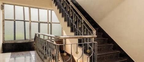 Un interior espacioso con escalera, ventanas amplias y suelo pulido.