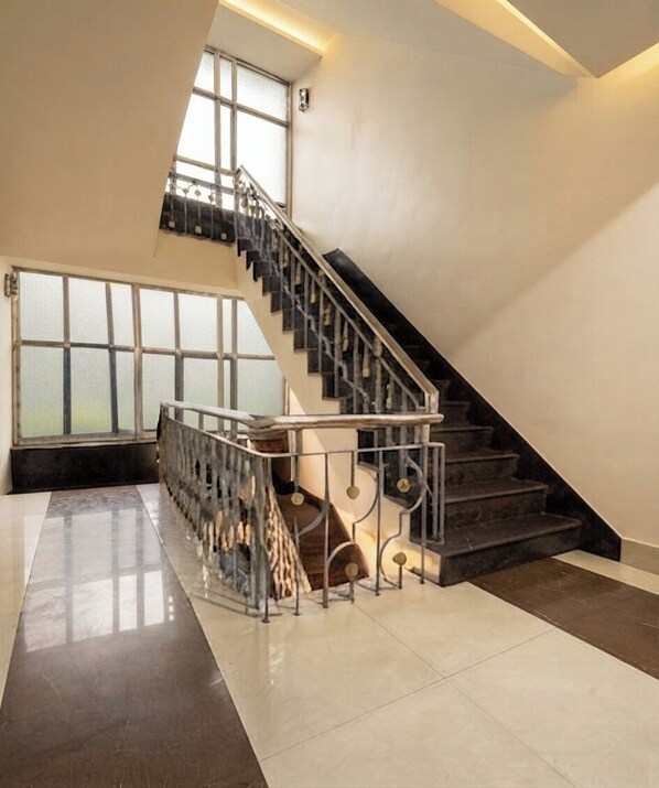 A spacious interior with a staircase, large windows, and a polished floor.