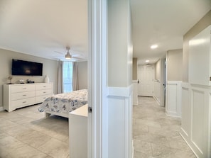 A bedroom with a bed, dresser, TV, and a ceiling fan. - Pelican Walk 612 Beachfront BLISS! 3Bedroom Condo (Panama City Beach)