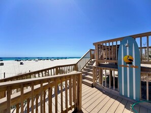 Eine Holzterrasse führt zu einem Strand, mit einem Schild für den Pelican Walk.