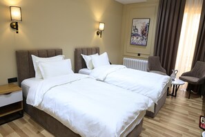 Una camera d'albergo con due letti, un comodino, una sedia e un quadro appeso al muro.