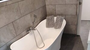 Ein modernes Badezimmer mit einer freistehenden Badewanne, einer Duschbrause und einem Handtuchhalter.