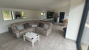 Ein modernes Wohnzimmer mit einer Eckcouch, einem Couchtisch und einer Küchenzeile im Hintergrund.