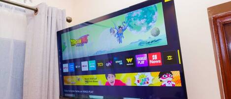 A flat-screen TV mounted on a wall displaying a streaming service interface with various app icons.