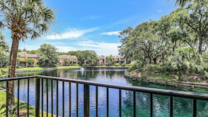 A tranquil outdoor pool area with a clear view of a building complex in the background. - Sunset Rentals | Island Club 101 (Hilton Head Island)