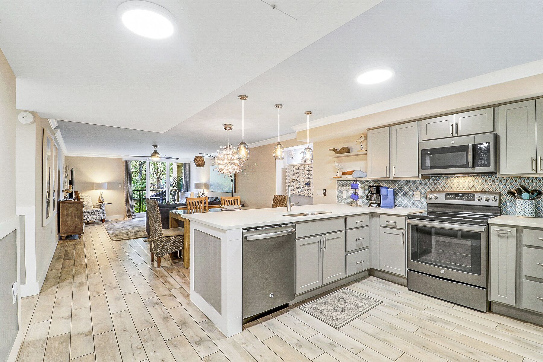 A modern kitchen with stainless steel appliances, a central island, and a dining area with a view.