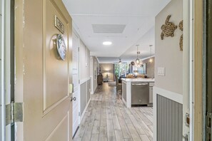 Ein Flur mit Küchenbereich, mit Holzboden, weißen Wänden und einer Decke mit Einbauleuchten.