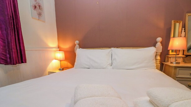 A neatly made bed with white linens and two bedside lamps. - Hillside Cottage (Windermere)