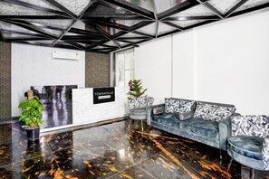 Ein Empfangsbereich mit Marmorboden, einer Couch mit gemusterten Kissen, einer Zimmerpflanze und einem Schild mit der Aufschrift 'TOWNHOUSE & Company Services'.