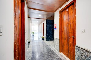 Un pasillo con puertas de madera, un extintor y suelo de mármol.