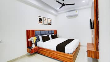 Een slaapkamer met een houten bedframe, een plafondventilator, een airconditioning en een aan de muur bevestigde televisie.