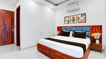 A modern hotel room with a wooden bed frame, a blue headboard, and a small bedside table with a vase of flowers.