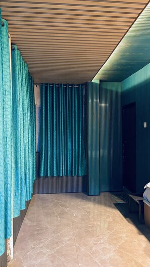 Una habitació amb sostre inclinat, cortina amb disseny, una panxa i una porta.
