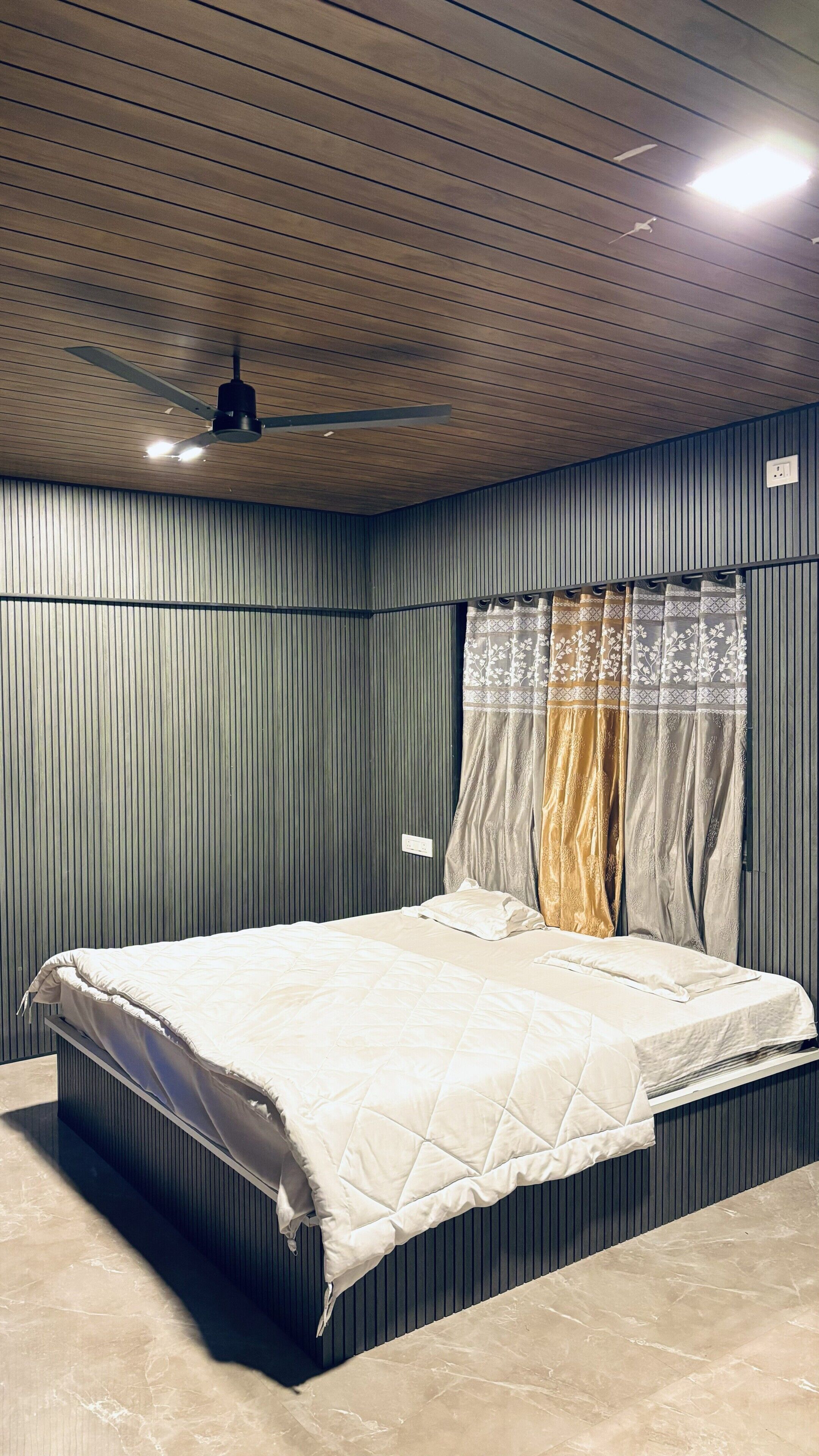 A bedroom with a bed, a ceiling fan, and a window with curtains.