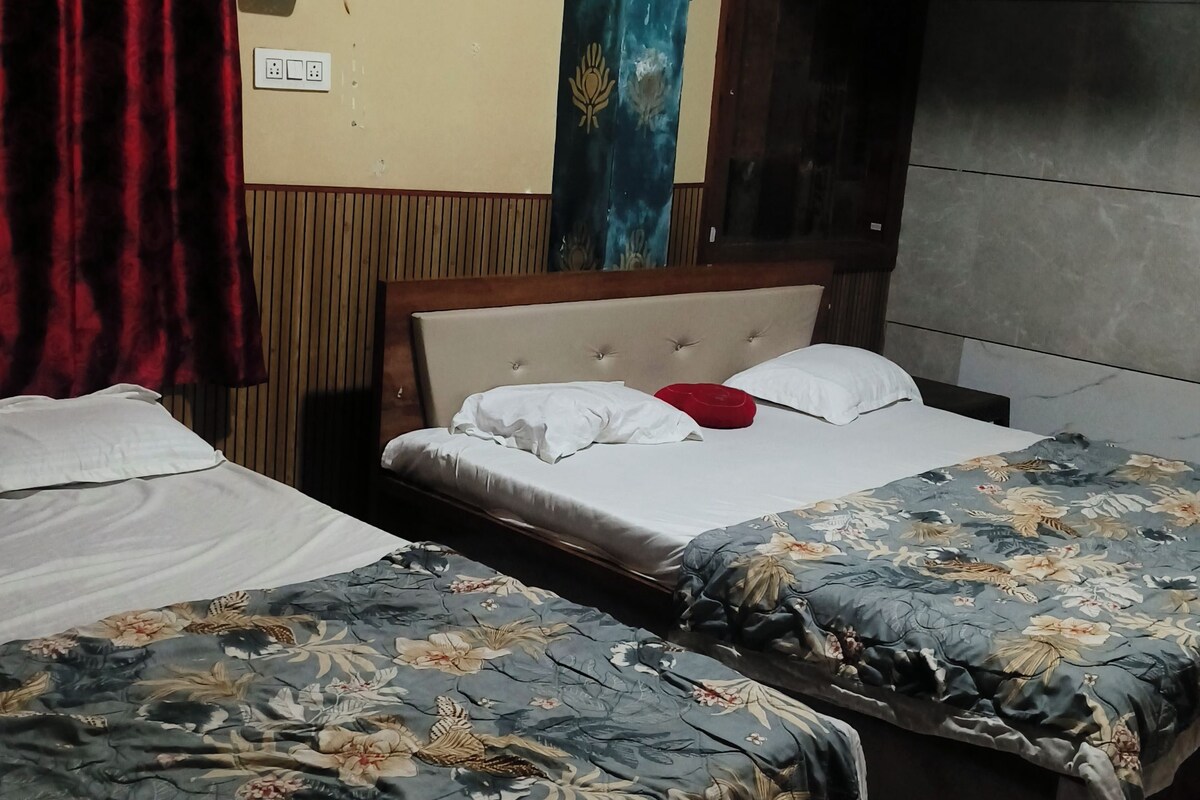 Habitació d'hotel amb dos llits, un reposacapses de fusta, una cortina i aire condicionat fixat a la paret.