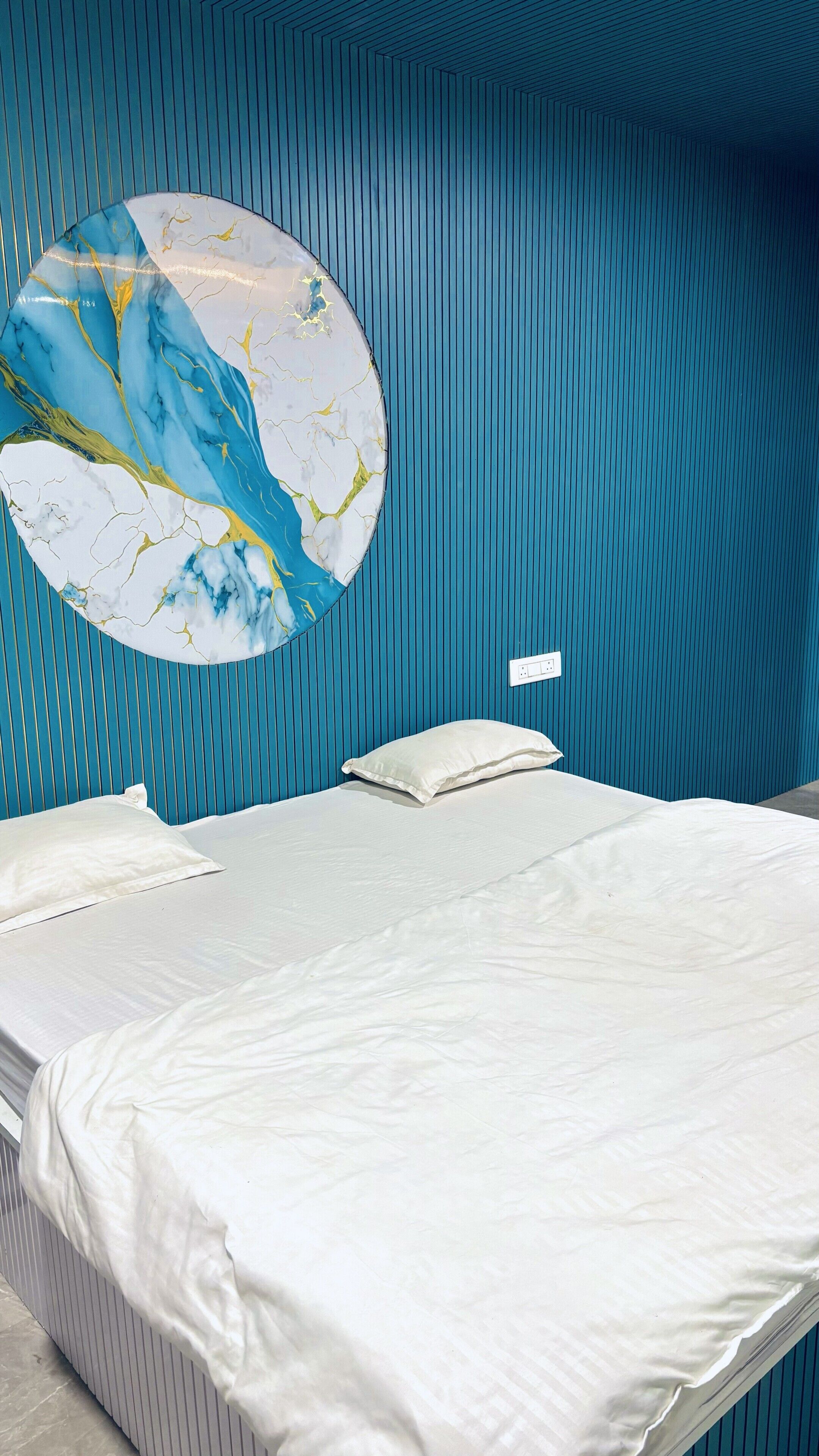 A bed with white bedding, a circular wall decoration, and a blue striped wall.