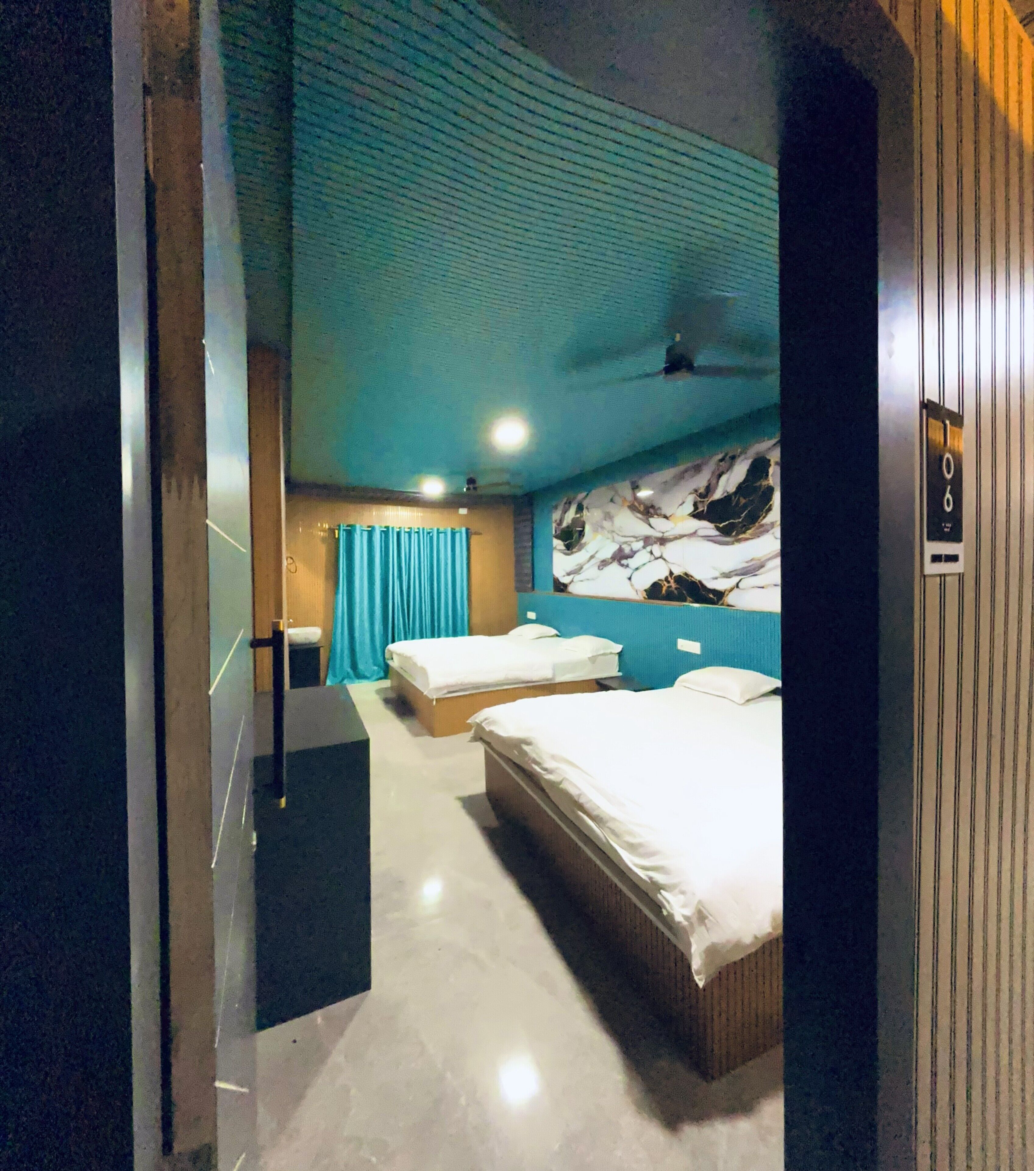 A hotel room with two beds, a bathroom, and a large window with curtains.
