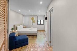 A bedroom with a bed, bedside table, and a chair. - Casa Costa Brava | 8 Room - 16 Guest @ San Juan (San Juan de Puerto Rico)