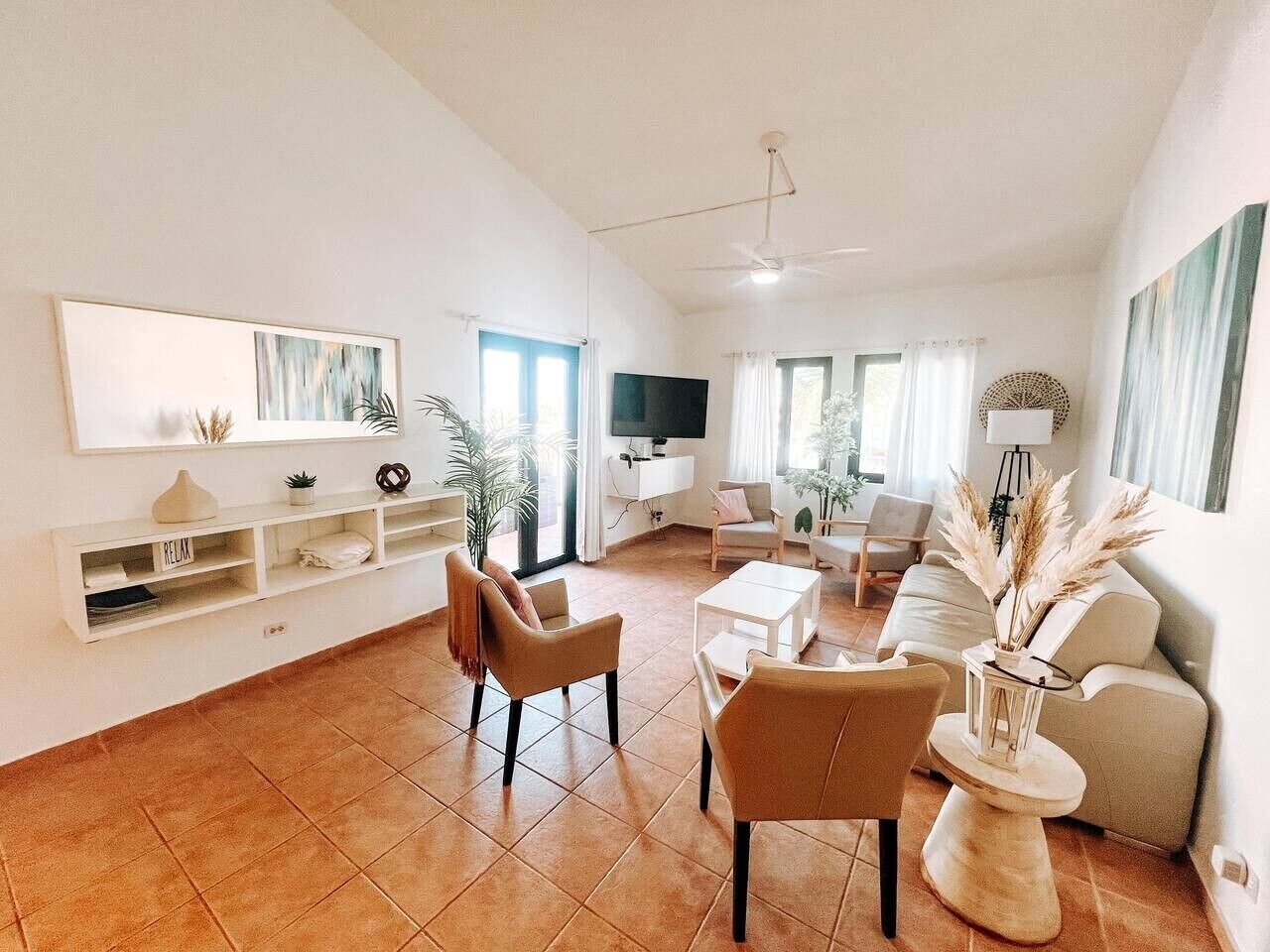 A spacious living room with a sofa set, a coffee table, and a TV mounted on the wall.