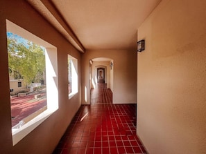 A corridor with tiled flooring, large windows, and a wall-mounted light fixture. - Peaceful Getaway w/ Beautiful Marina Views (Palmas del Mar)