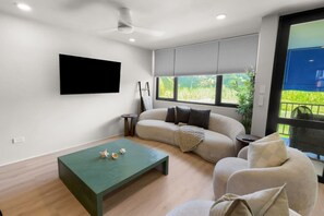 A modern living room with a sofa, a coffee table, and a TV mounted on the wall. - Villa Marena | Playas del Yunque Modern Apt (Rio Grande)