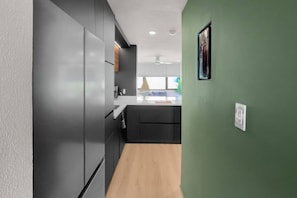 A modern kitchen with dark cabinetry, a wooden countertop, and a green wall. - Villa Marena | Playas del Yunque Modern Apt (Rio Grande)
