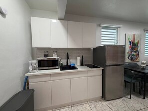 A compact kitchen with white cabinets, a stainless steel refrigerator, a microwave, and a sink. - Central San Juan 3BR Apt • Sleeps 8 (San Juan de Puerto Rico)