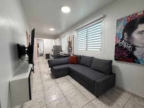 A modern living room with a sectional sofa, a flat-screen TV, and artwork on the walls. - Central San Juan 3BR Apt • Sleeps 8 (San Juan de Puerto Rico)