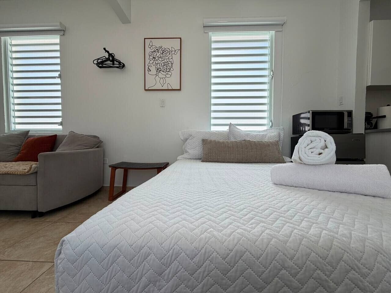 Ein Schlafzimmer mit einem großen Bett, einer Couch, einem kleinen Tisch und einer Mikrowelle.