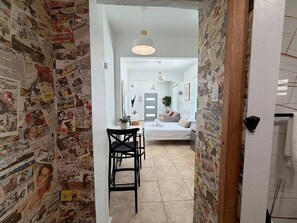 Ein Flur mit Essbereich, einem Bett und einem Badezimmer im Hintergrund.