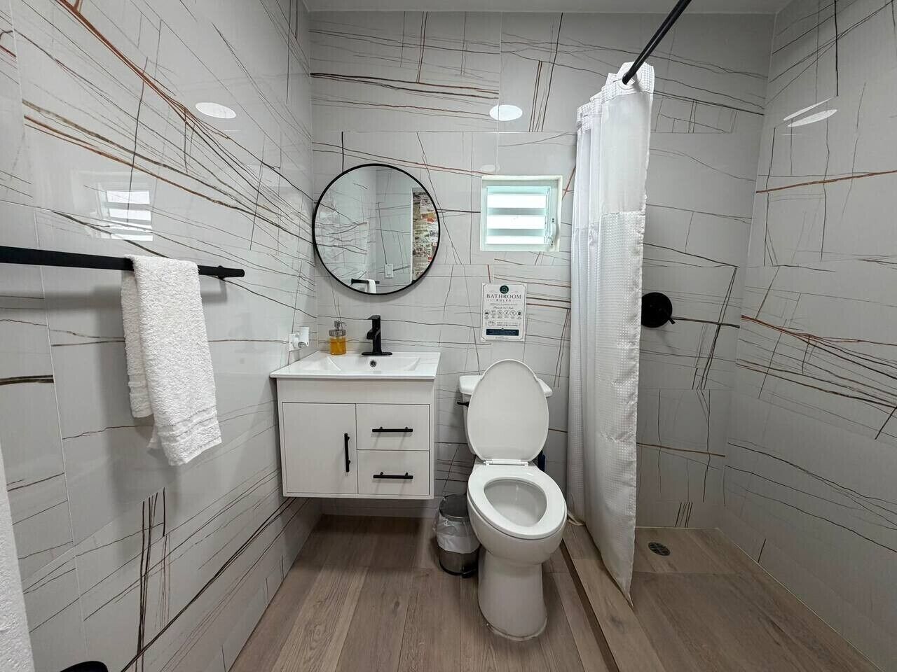 A bathroom with a toilet, sink, mirror, and towel rack.