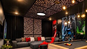 Ein modernes Wohnzimmer mit Billardtisch, Ecksofa und einer Wand mit vertikalen Paneelen.