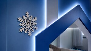 Ein modernes Interieur mit geometrischem Design, einer Schneeflocken-Dekoration und einem Bett mit Blick in einen anderen Raum.