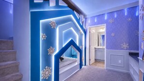 Ein Flur mit blauer Akzentwand, einer Treppe und einem durch eine offene Tür einsehbaren Badezimmer.