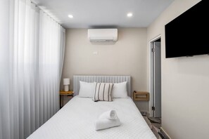A hotel room with a bed, a TV, an air conditioner, and a window with curtains. - Costa Brava Apt 1 | Calle Loiza Cozy @ San Juan (San Juan de Puerto Rico)